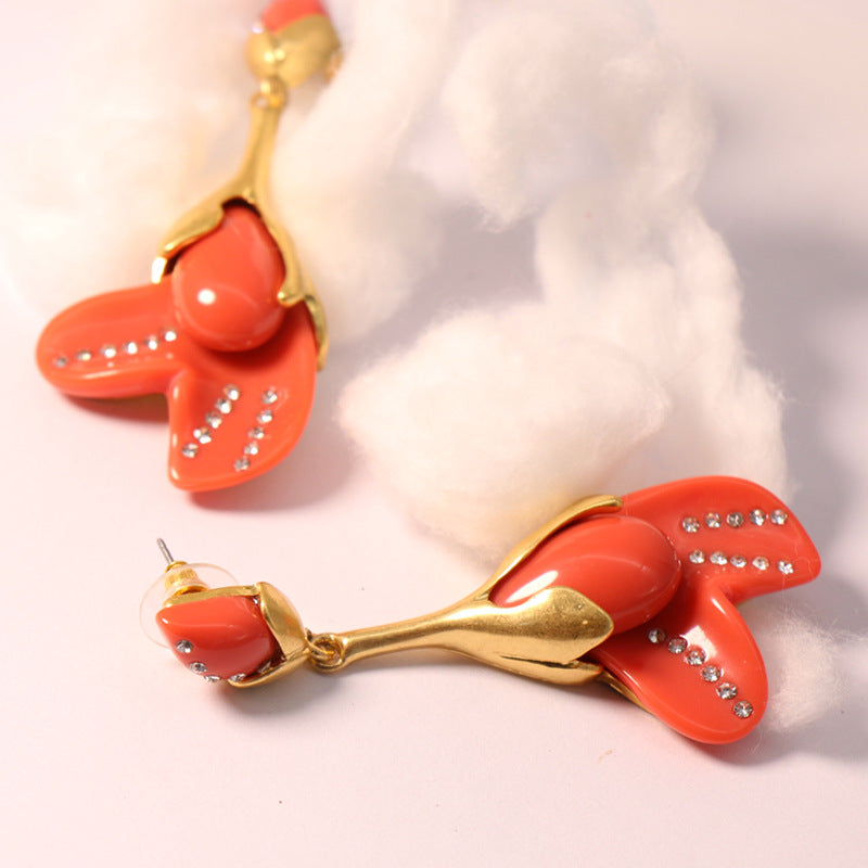 Coral red resin floral stud earrings with gold-tone settings and rhinestone detailing