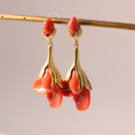 Coral red resin floral drop earrings with gold-tone petals and rhinestone accents