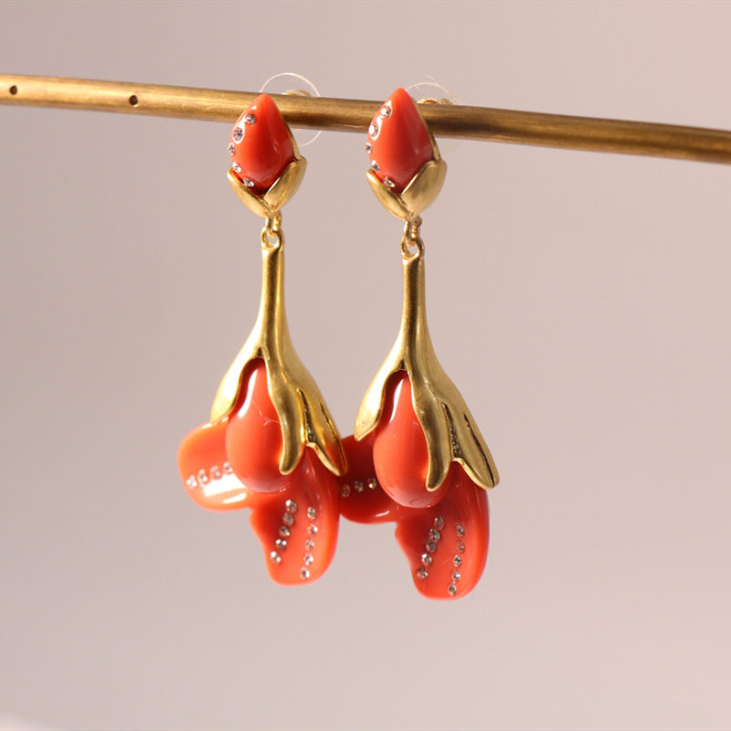 Coral red resin floral drop earrings with gold-tone petals and rhinestone accents