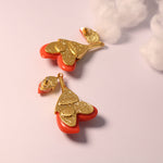 Coral red resin floral drop earrings with gold-tone textured caps and petal shapes
