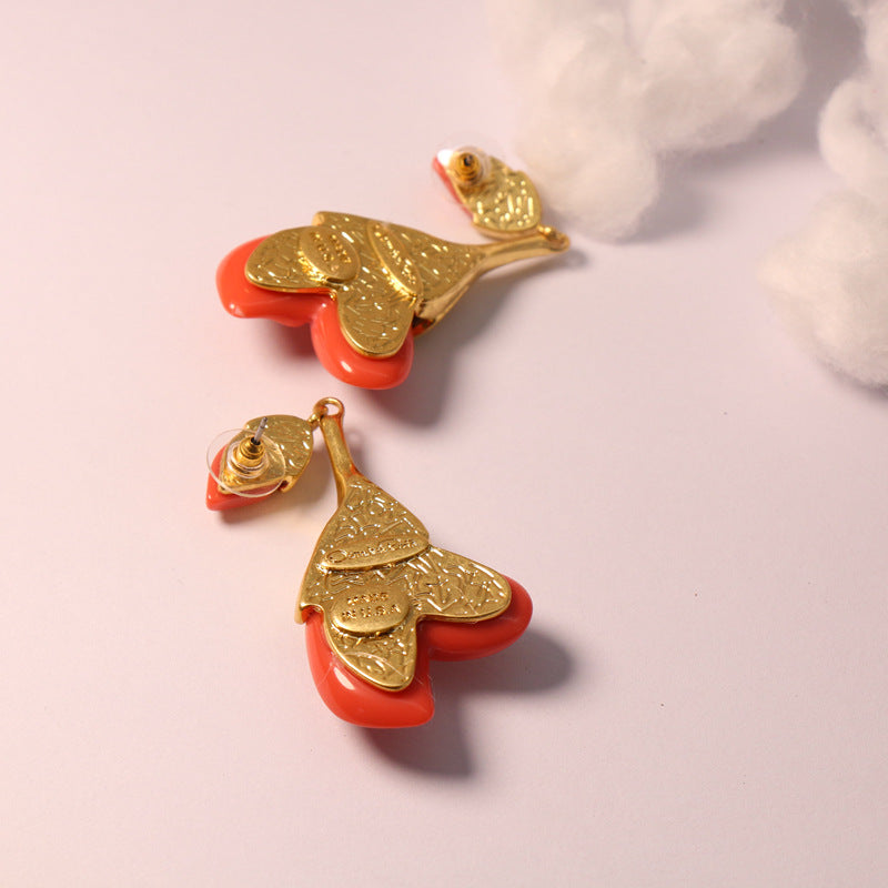 Coral red resin floral drop earrings with gold-tone textured caps and petal shapes
