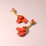 Coral red resin floral earrings with gold-tone petal design and rhinestone rows