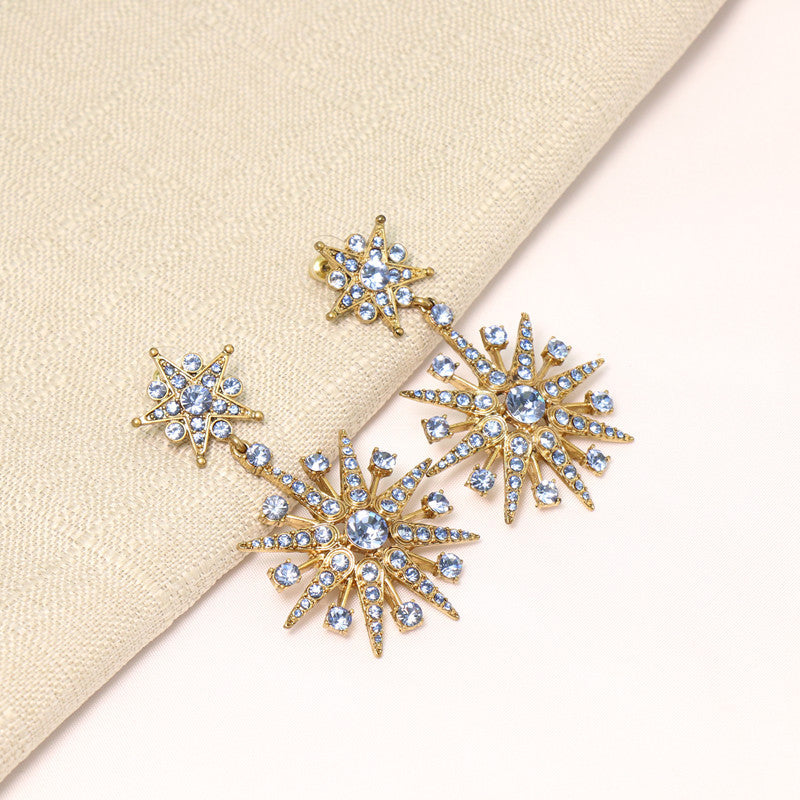Light blue crystal star drop earrings, gold-tone with eight-pointed star studs.