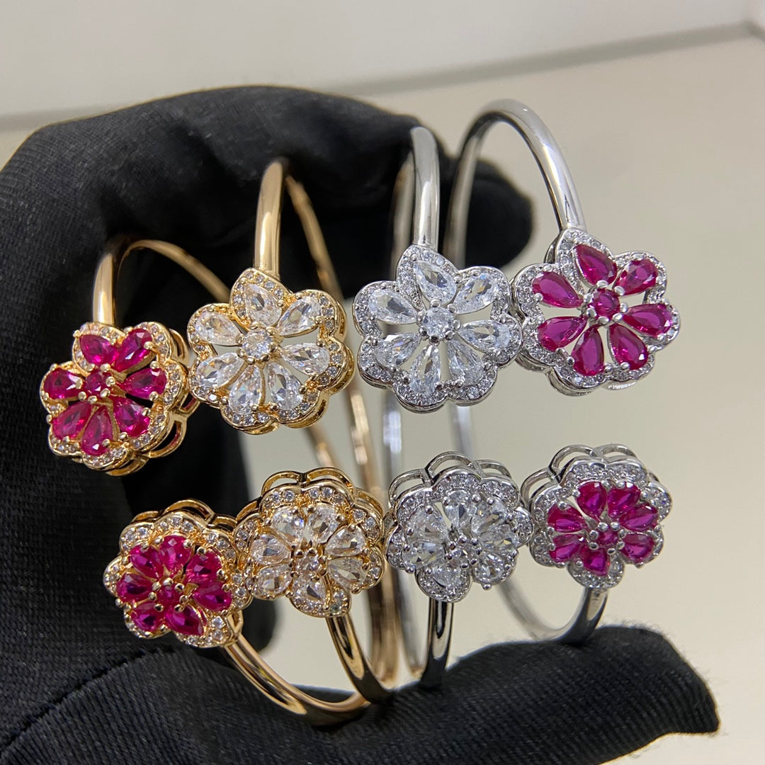 Mehrere Armreifen mit Blumenmotiven: klar, goldfarben und pink, teils in Weißgoldoptik