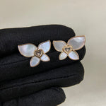 Butterfly earrings with iridescent mother-of-pearl petals, heart center, and gold-tone frames