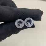 Round diamond-studded stud earrings in white-gold tone, on dark knit fabric