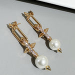 Gold-tone hoop earrings with white pearls, rhinestone sparkle bar and bow accents