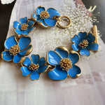Enamel floral bracelet with gold-tone chain, bright blue petals, and bead-centered flowers