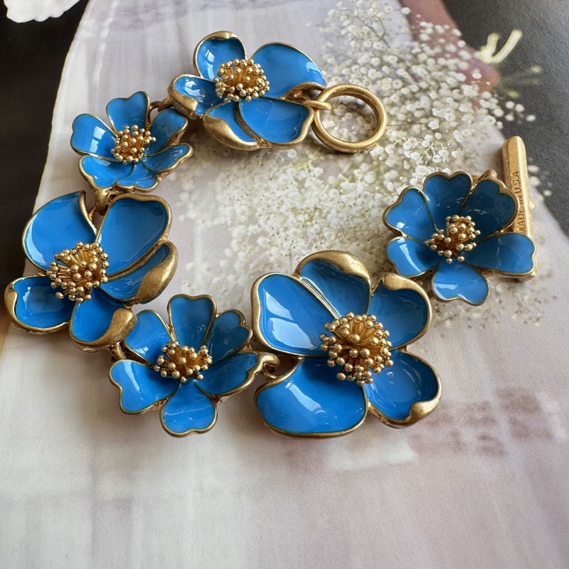 Enamel floral bracelet with gold-tone chain, bright blue petals, and bead-centered flowers