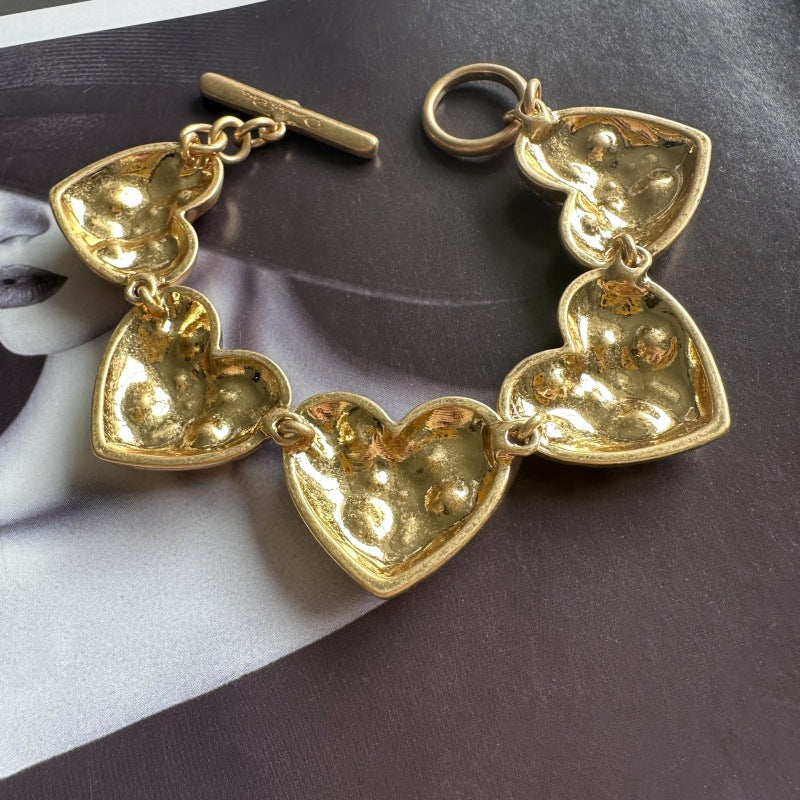 Gold-tone heart bracelet with five openwork heart charms and ring clasp