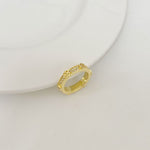 Gold-tone rhinestone band ring, angled view of round stone setting