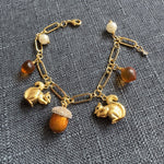 Gold-tone charm bracelet with squirrel, acorn, pinecone and pearl accents, chain links