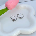 White gold hoop earrings, side view of clover logo charm