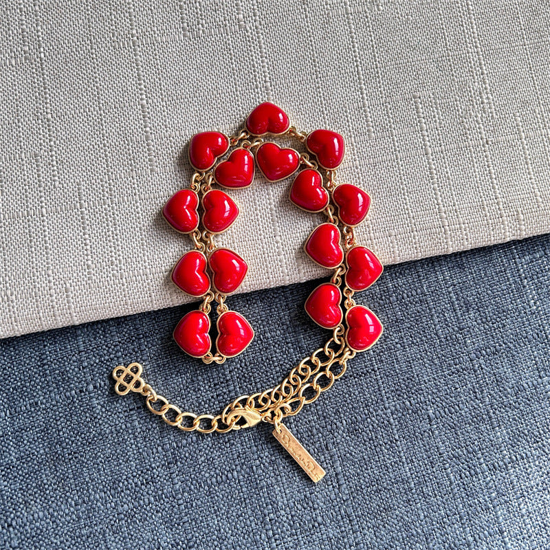 Heart-shaped necklace with red enamel heart charms and gold chain clasp