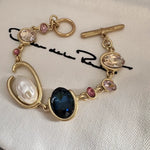 O-ring crystal pearl bracelet, gold tone with dark oval center stone, pink crystals and pearl