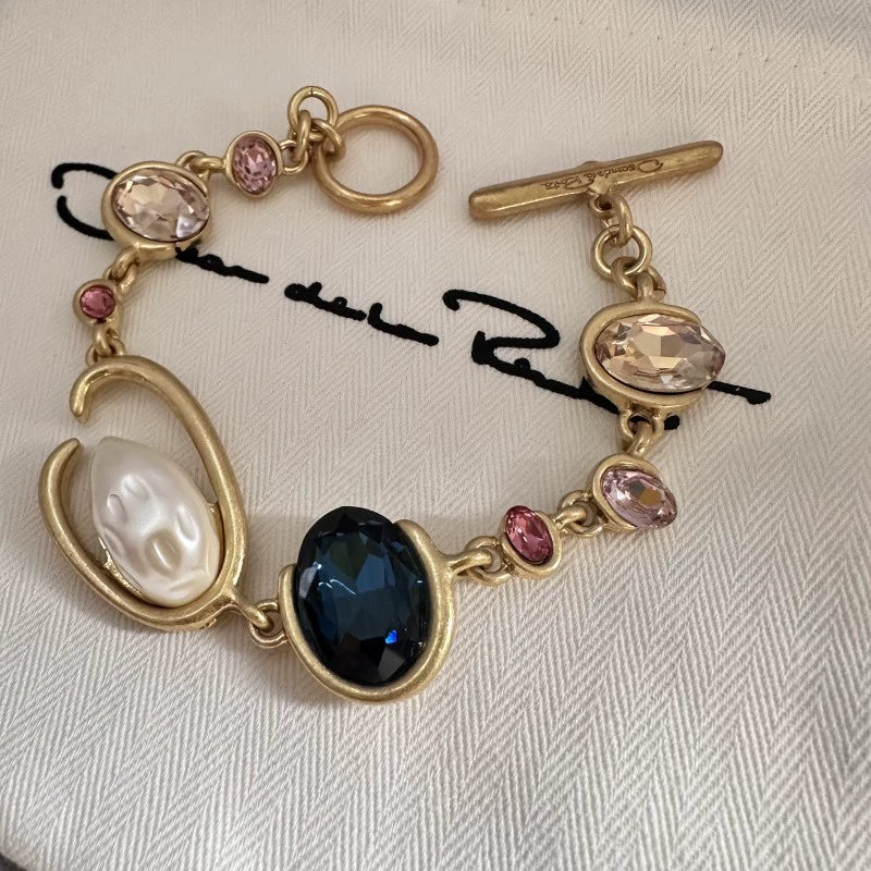 O-ring crystal pearl bracelet, gold tone with dark oval center stone, pink crystals and pearl