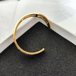 Gold openwork logo bangle bracelet with inner curve and engraved logo band