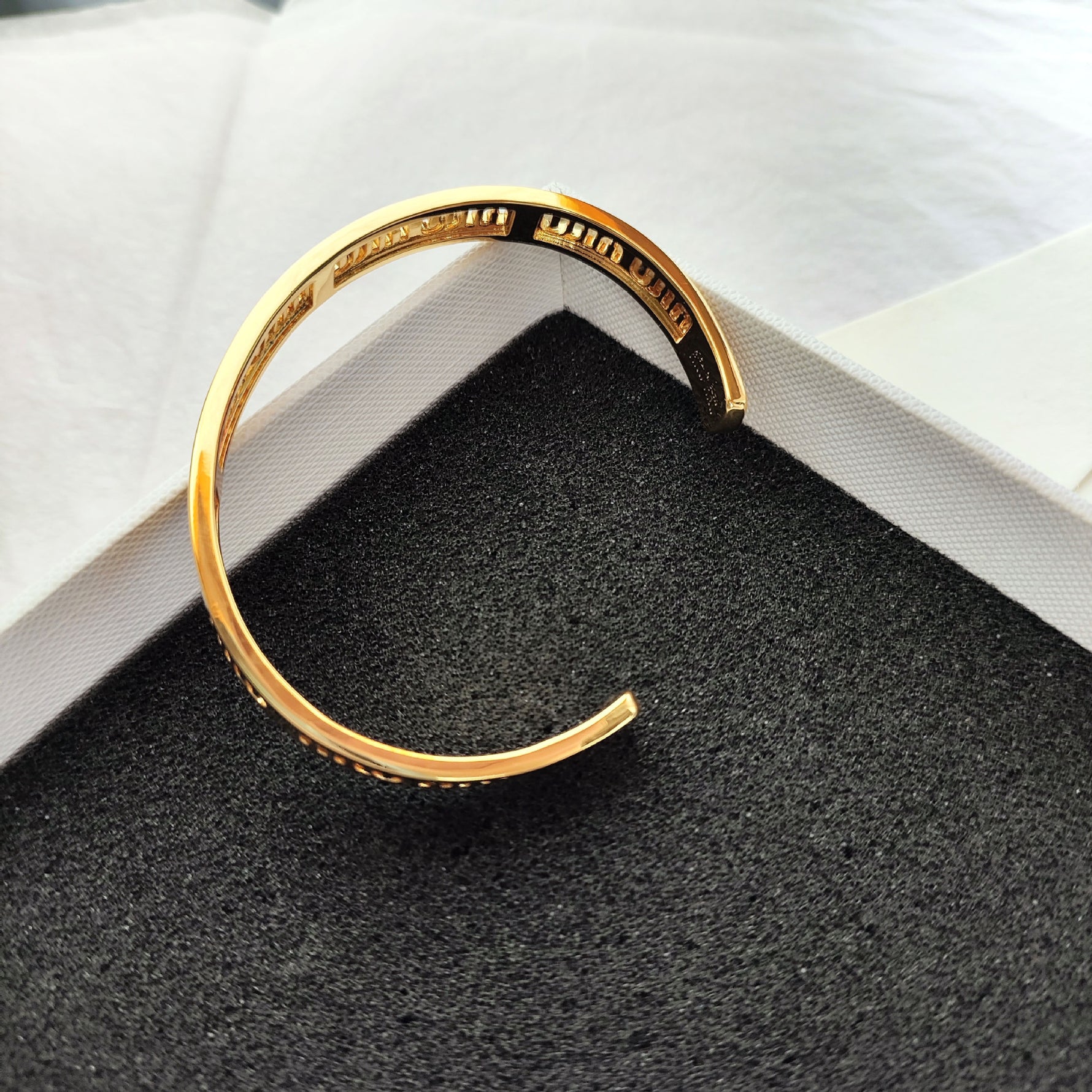 Gold openwork logo bangle bracelet with inner curve and engraved logo band