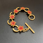 Rotes Blumenarmband mit goldfarbenen Gliedern und funkelnden Steinen, plus T-Knopf