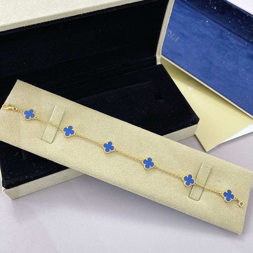 Gold tone bracelet with bright blue clover charms on a delicate chain