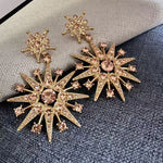 Rose-gold star drop earrings with pink crystal eight-point stars and dangling charms.