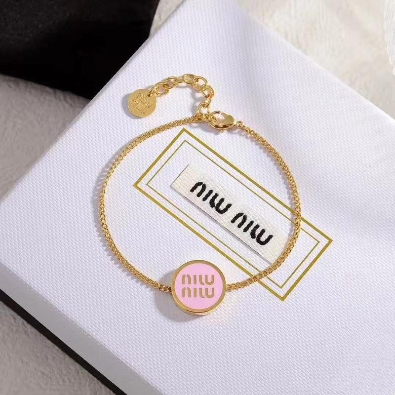 Round pink enamel charm bracelet with gold chain and adjustable metal clasp.