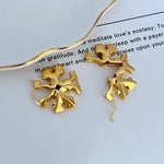 Gold 3D logo metal hoop earrings, sculpted floral emblem, hanging view