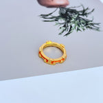 Gold-tone enamel geometric circle ring with red enamel accents around the band