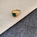 Square gemstone ring with deep emerald green stone in textured gold band