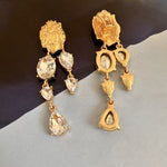 Gold crystal tassel earrings with clear teardrop stones and ornate drop charms