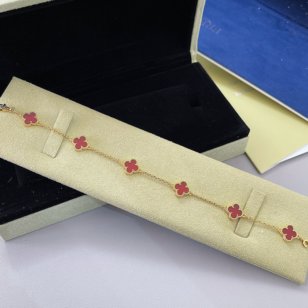 Goldfarbenes Armband mit vierblättrigen Kleeblatt-Anhängern mit rotem Akzent
