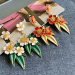 Red enamel floral drop earrings with gold beaded flowers and pointed gold leaf details