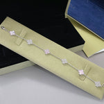 Silberfarbenes Armband mit helllila Vierblatt-Anhängern und strassbesetzten Gliedern
