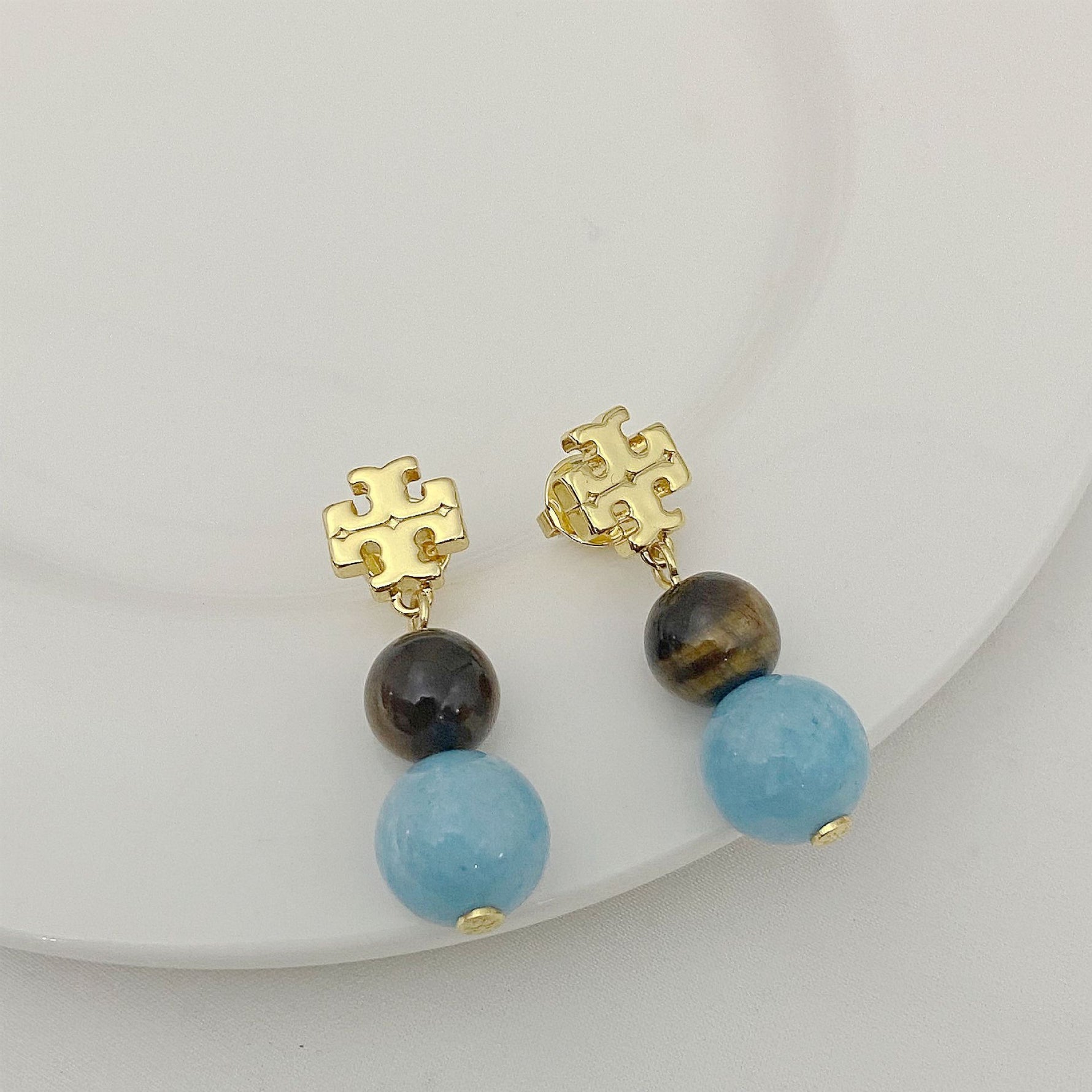 Gold logo pendant earrings with dark and light blue agate beads, drop style