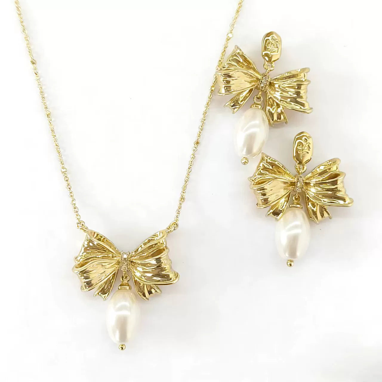 Bow pendant necklace with white pearl drop, paired with matching stud earrings