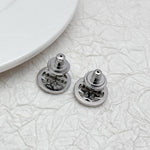 White-gold logo stud earrings with rhinestone rim, shown with back posts