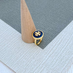 Round enamel metal ring with dark blue shell center on gold-tone band