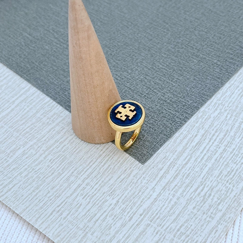 Round enamel metal ring with dark blue shell center on gold-tone band