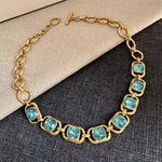 Gold link necklace with turquoise-blue faceted crystal oval stations