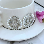 White gold round logo metal earrings with pearl halo and small hook backs