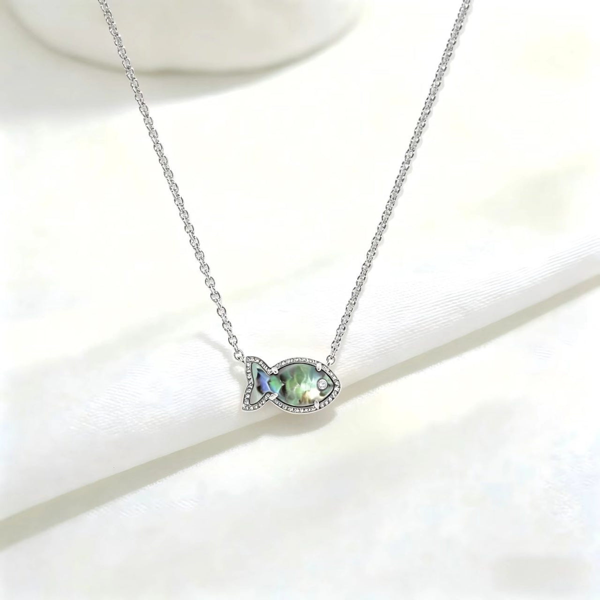 Fish-shaped iridescent pendant necklace, silver tone with small stones