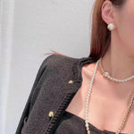 Pearl stud earrings on model ear, gold-tone setting with rounded frame