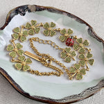 Four-leaf clover necklace with red ladybug charm, gold chain, scattered clover details