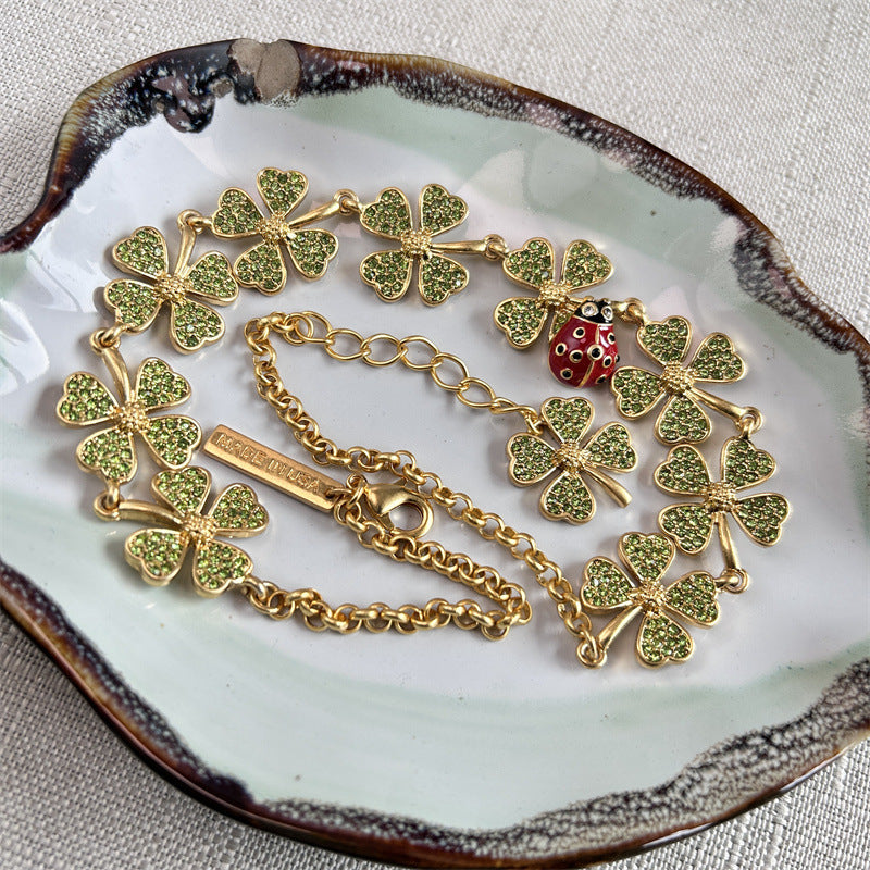 Four-leaf clover necklace with red ladybug charm, gold chain, scattered clover details