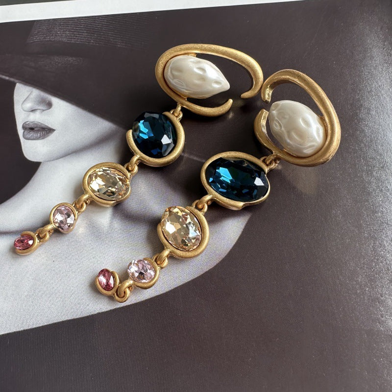 Long crystal drop earrings in gold with dark blue, champagne, and small pink crystals