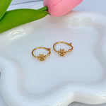 Gold hoop earrings with clover logo charm, hinged hoop detail