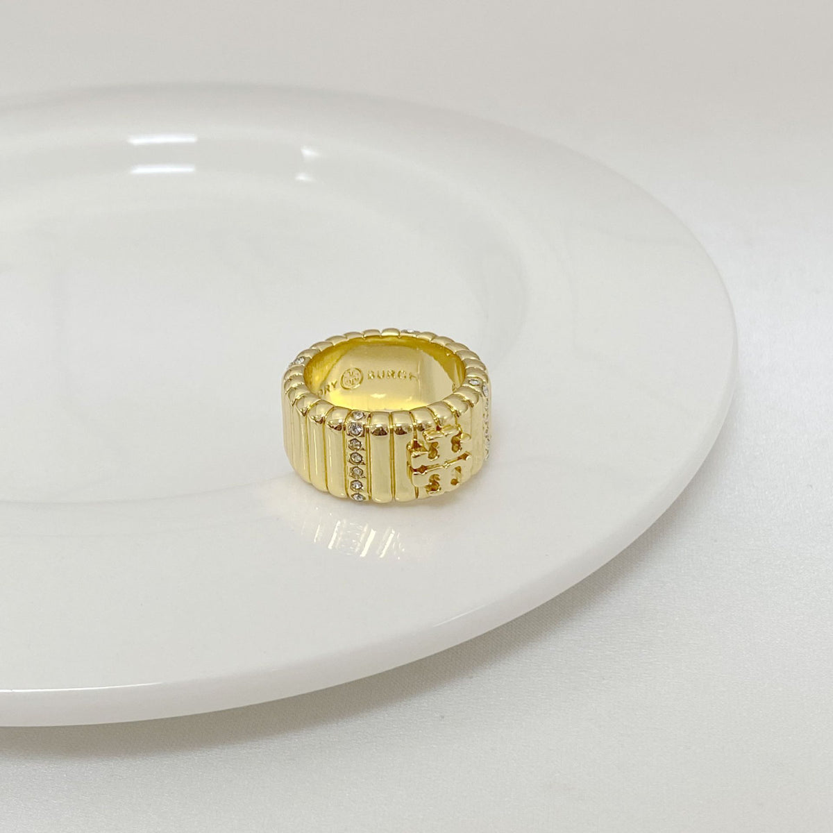 Gold metal ring with vertical striped band and rhinestone accents