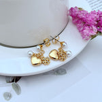 Gold heart earrings with pearl drops and crystal-like rhinestone accents on links