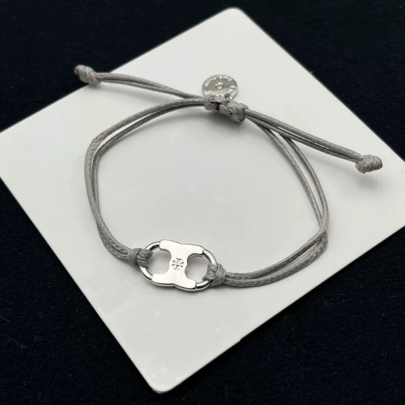 Gray woven adjustable drawstring bracelet with silver-tone clover enamel charm and coin tag