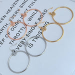 Round hoop earrings in rose gold, gold, and silver with small quatrefoil charm